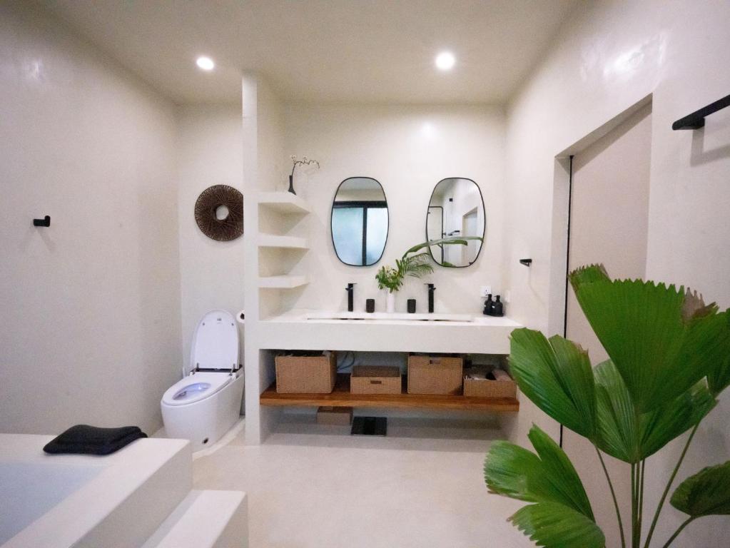 ein Badezimmer mit Waschbecken, Toilette und Spiegel in der Unterkunft Villa Nomada Luxury 5 BDR Villa SEAVIEW in Ban Bang Po