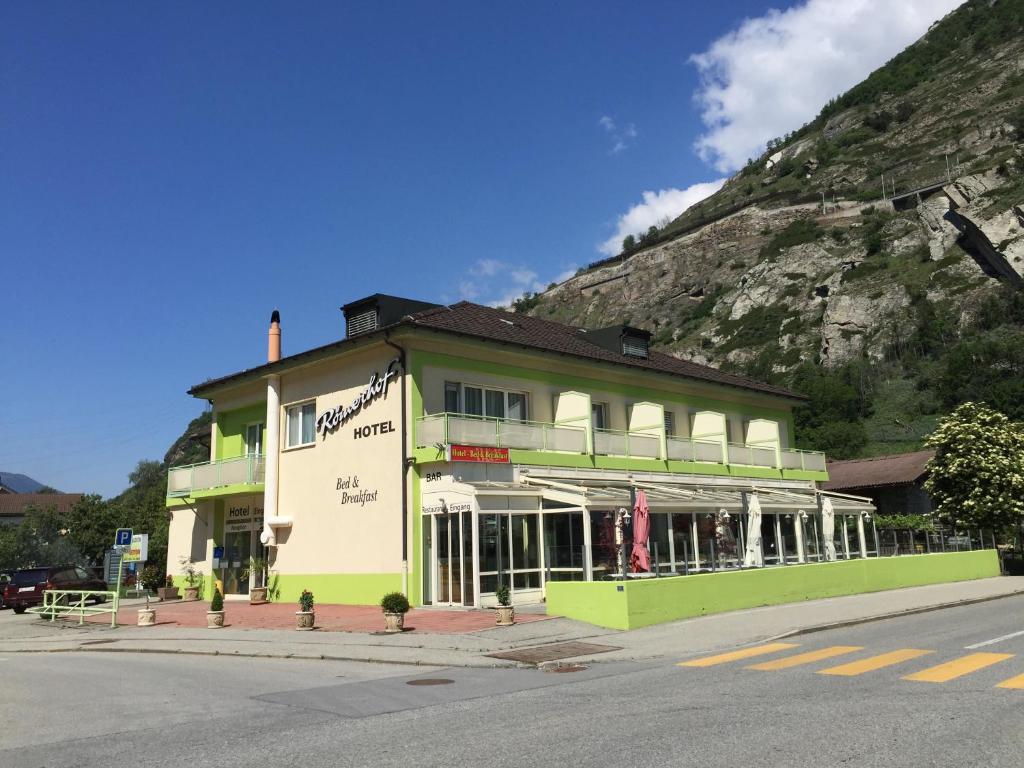 a green and white building on a street with a mountain at Hotel Römerhof in Brigerbad