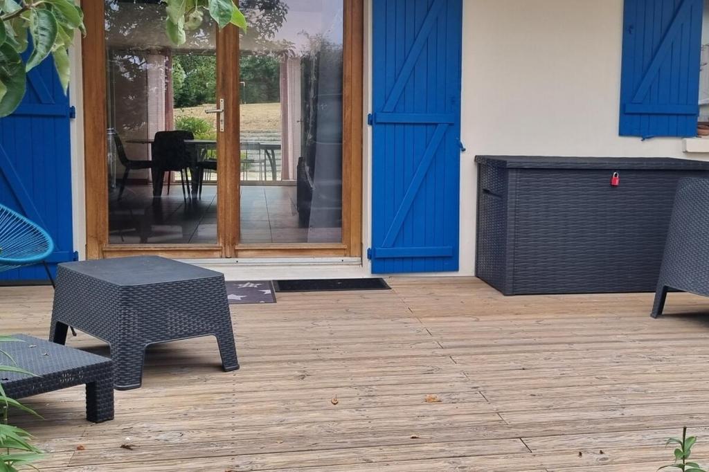 d'une terrasse avec des portes bleues, une table et des chaises. dans l'établissement Maison avec jardin à 1km de la plage du Val-André, à Pléneuf-Val-André