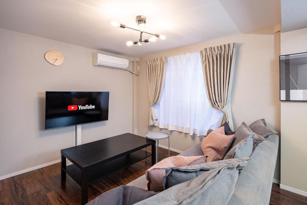 een woonkamer met een bank en een tafel bij アリタ日本橋西2F in Osaka