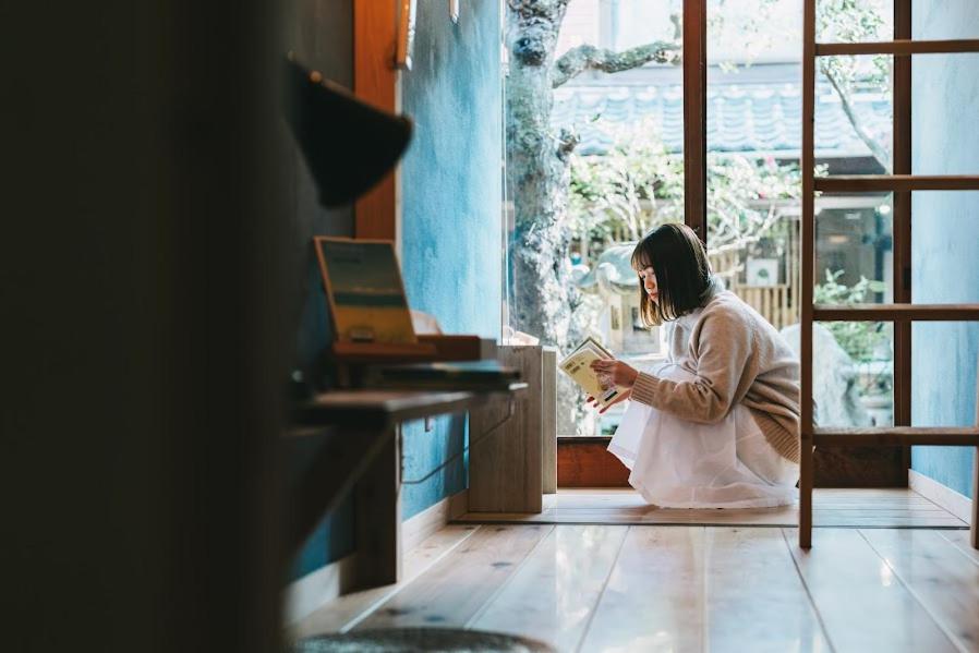 a woman sitting on the floor reading a book at うみの図書館 in Sanuki