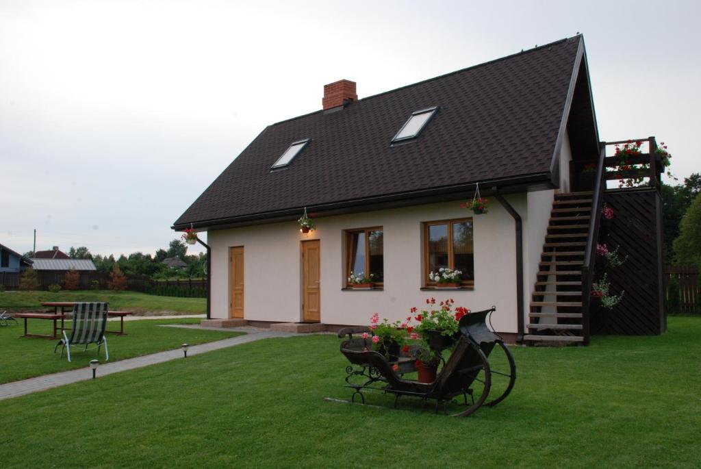 a small white house with a black roof at Brīvdienu Māja Riekstnieki in Plieņciems