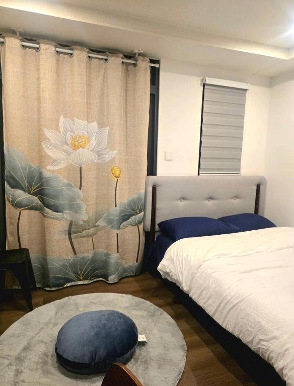 a bedroom with a bed and a window with a flower on the curtain at Liam and Linus Condo 1 Studio Type in Baguio