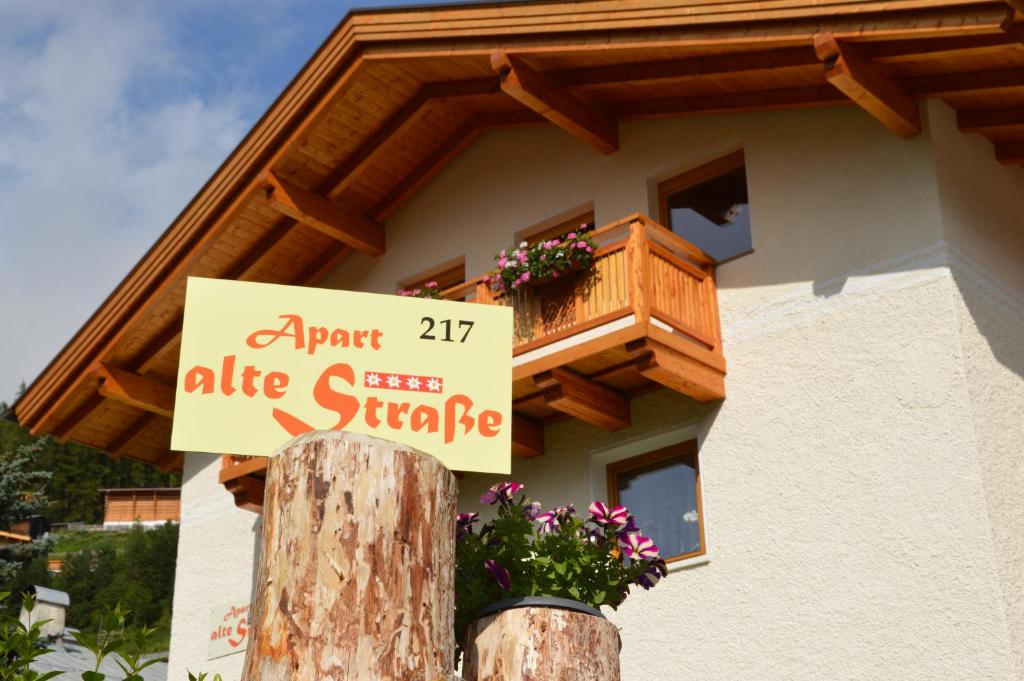 a sign on a tree stump in front of a house at Apart Alte Straße in Nauders