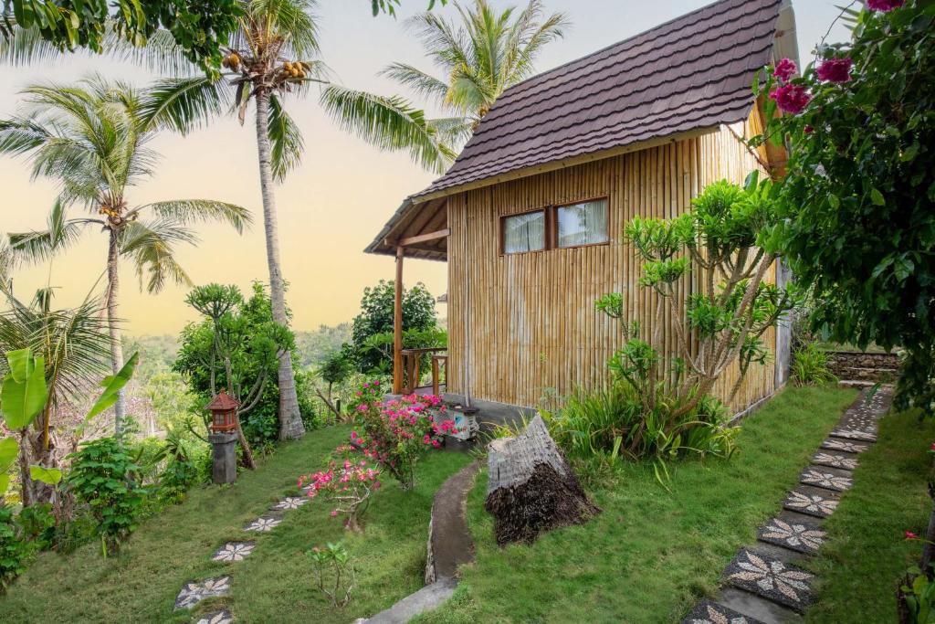 珀尼达岛艾杜森林小屋旅馆的一座种植了棕榈树和鲜花的小木房子