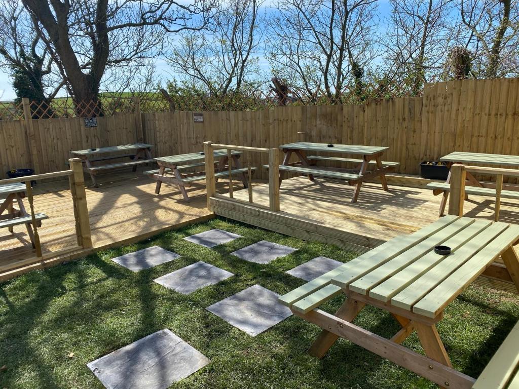 a patio with picnic tables and a fence at Holland Hotel in Llanfachraeth