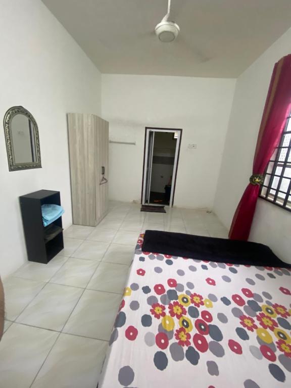 ein Schlafzimmer mit einem Bett mit einer bunten Bettdecke in der Unterkunft Wan Homestay in Kuala Terengganu
