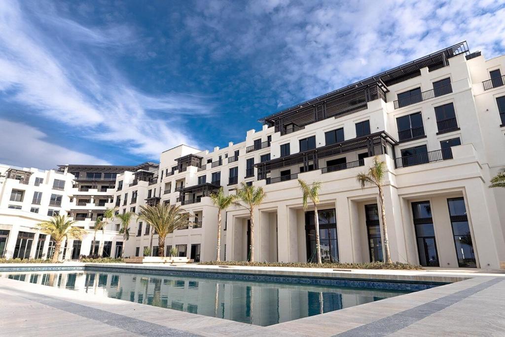 a large white building with a pool in front of it at Luxury Seaside Stay - SeaBreeze The Grand in Nardaran