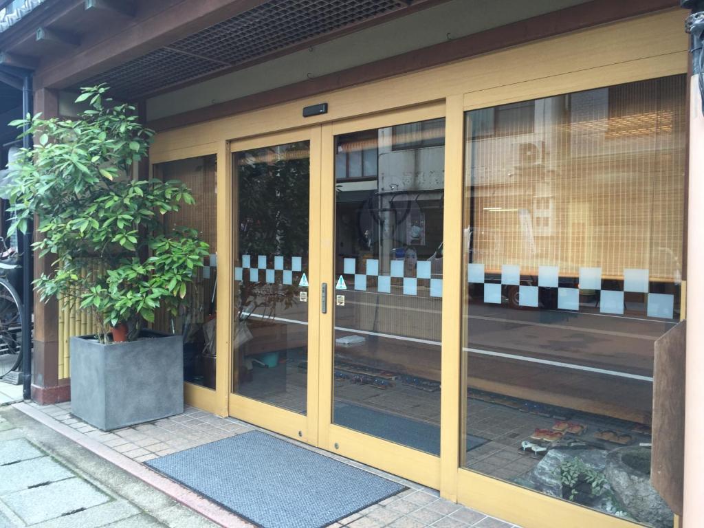 un negozio con porte in vetro e una pianta in vaso di Ryokan Mitsuwa a Toyooka