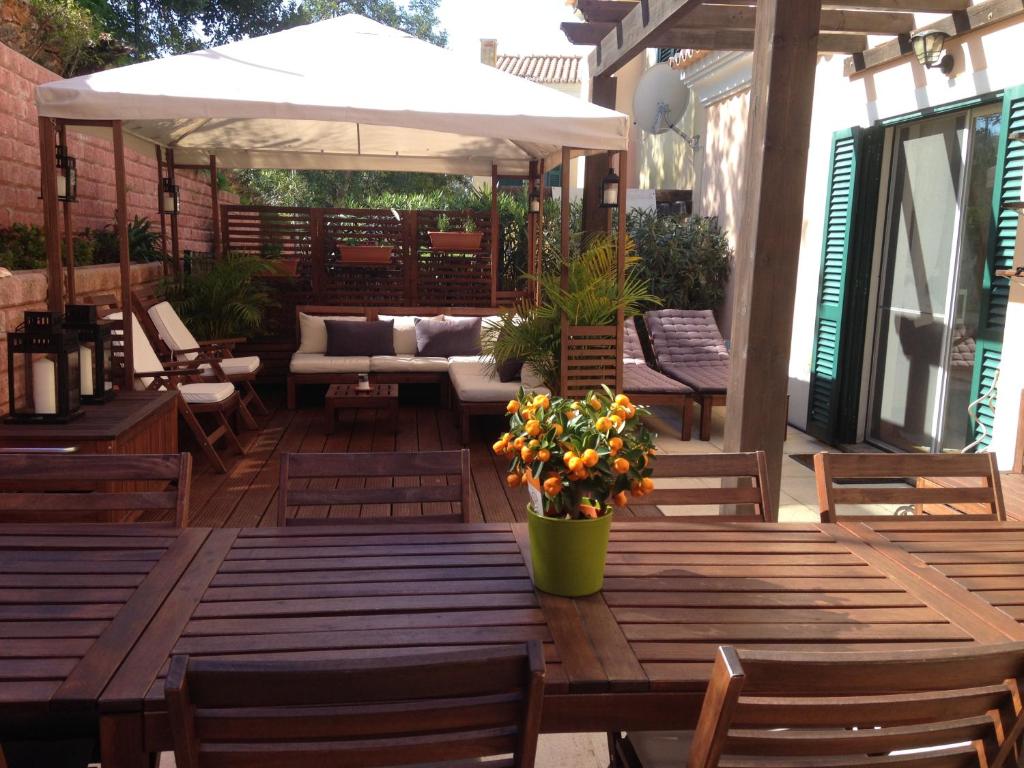 un patio con mesas y sillas de madera y una sombrilla en Casa Estelliane, en Paderne