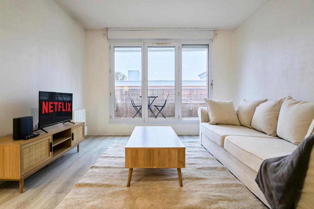 un salon avec un canapé et une télévision dans l'établissement Élégant appartement avec balcon privé à Lille, à Lille