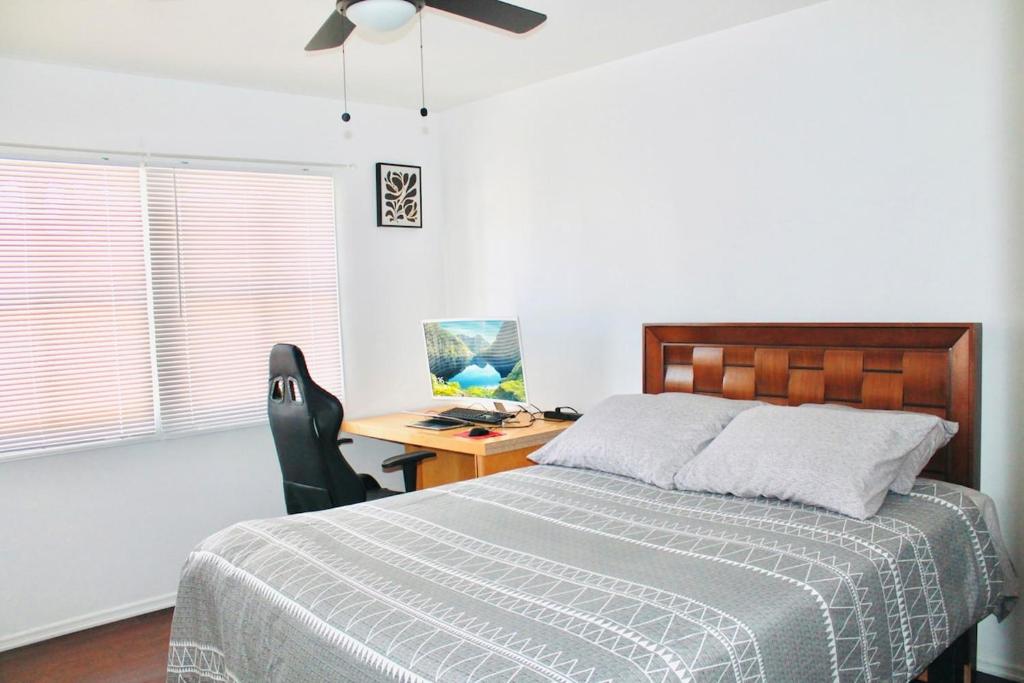 Un dormitorio con una cama y un escritorio con una computadora. en Los Angeles Red Rose, en Monterey Park