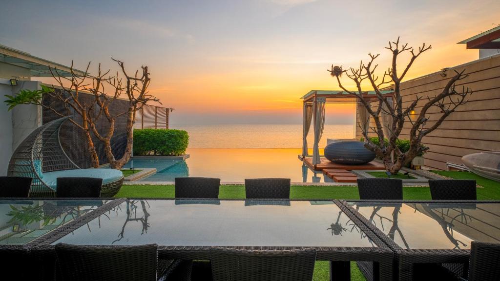 a pool with a view of the ocean at sunset at A Dream Hua Hin - Beachfront Retreat in HHQ