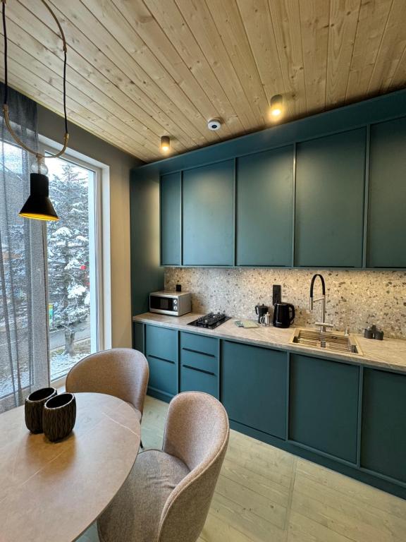 eine Küche mit blauen Schränken und einer Holzdecke in der Unterkunft Girske Povitria Apartments in Jaremtsche