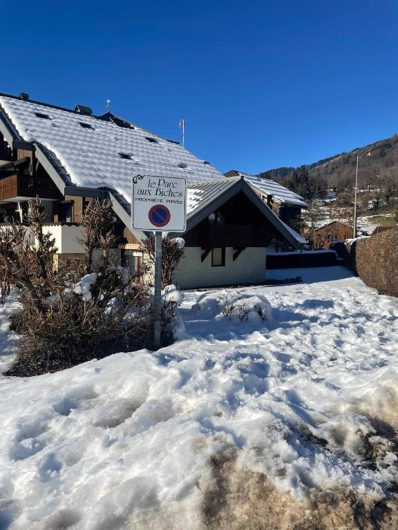 un panneau dans la neige devant une maison dans l'établissement Douceurs des Biches, à Samoëns