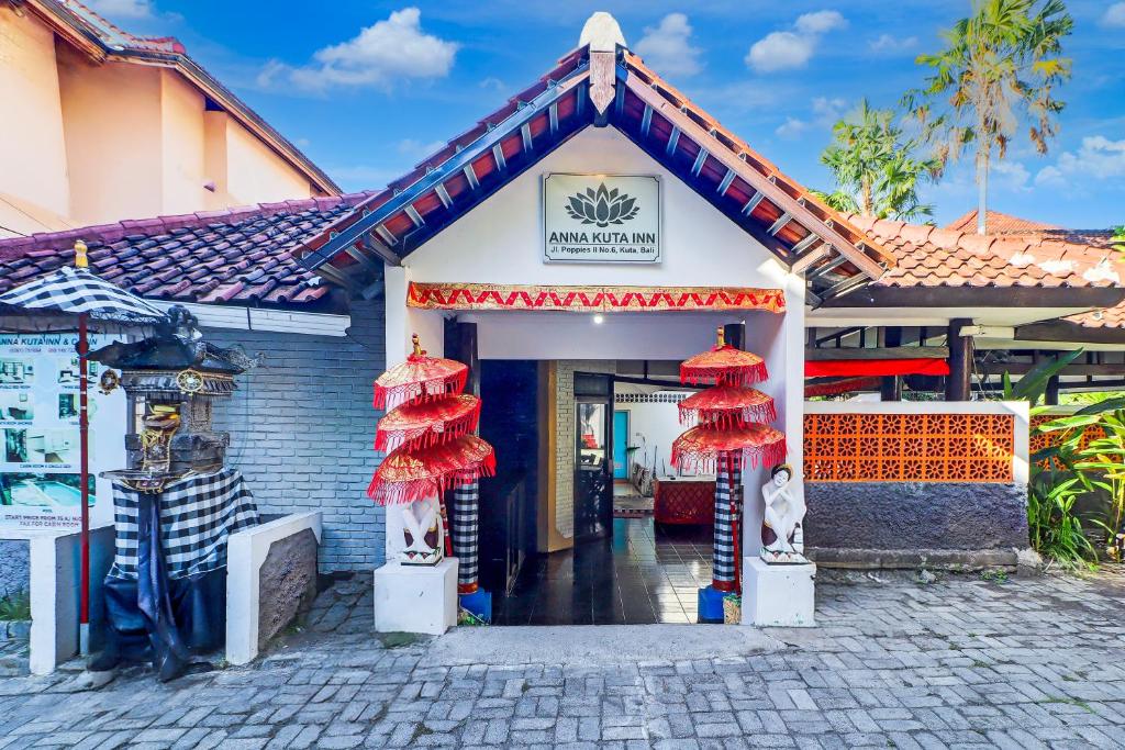 a building with red umbrellas in front of it at Collection O Legian Near Bimc Hospital Nusa Uda Formerly Anna Kuta Inn in Legian