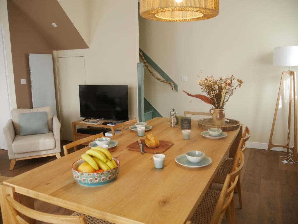une table en bois avec un bol de bananes et une télévision dans l'établissement TY LAOUEN - 1km des plages - Jardin - Wifi -, à Saint-Philibert