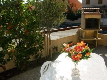 une table blanche avec un vase de fleurs sur elle dans l'établissement Maison 3 pièces - Gruissan Ayguades AY060-160, à Vires