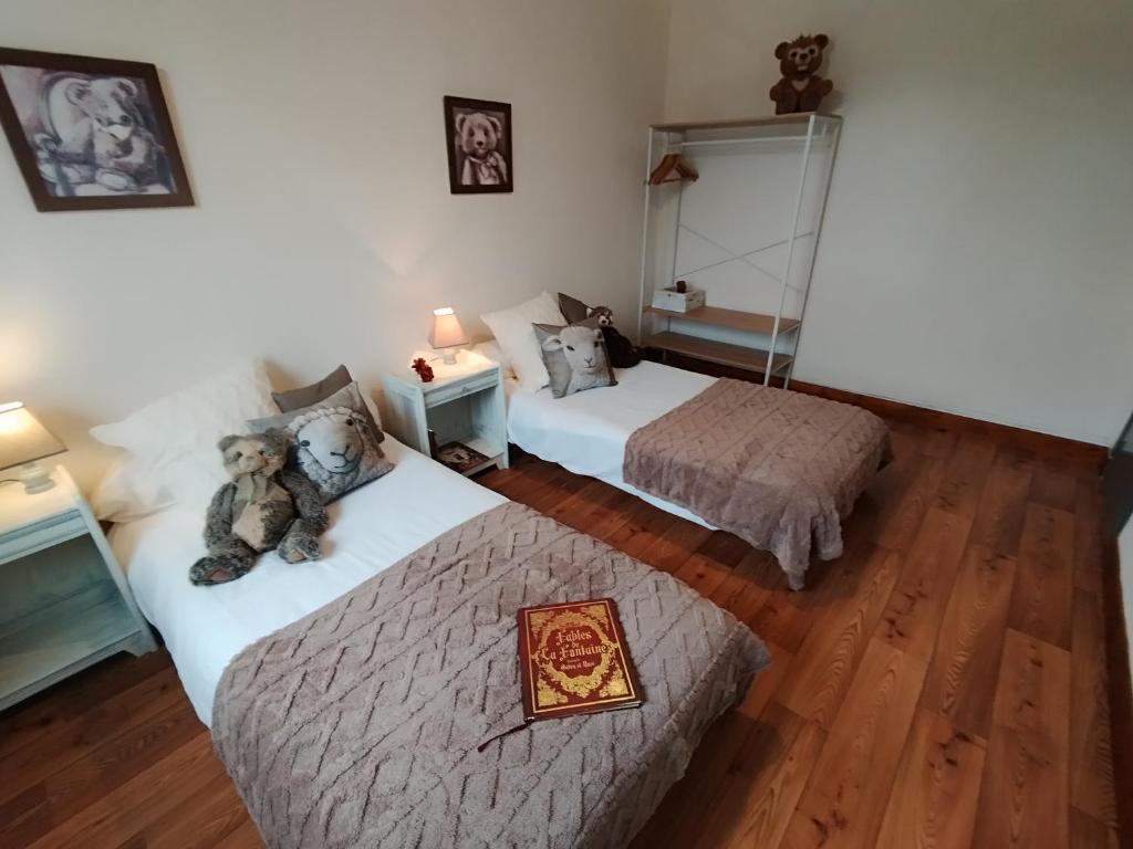 Deux lits dans une pièce avec un ours en peluche assis sur eux dans l'établissement Le Pavin confort - Résidence de Michèle Murol, à Murol