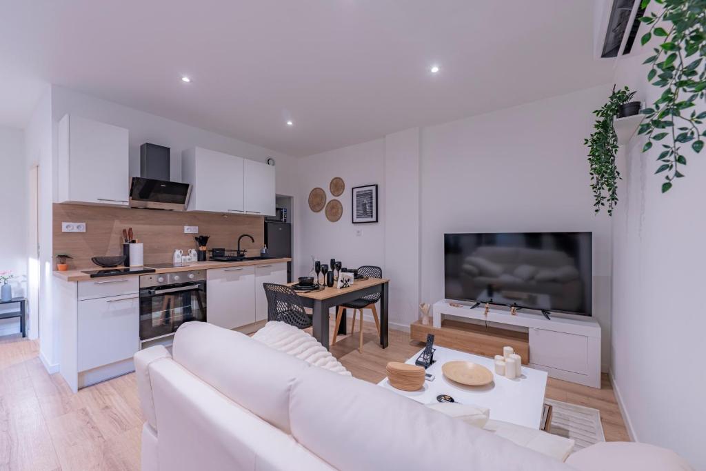 a living room with a white couch and a kitchen at Les Beaux Rêves - A 1h de Lyon in La Côte-Saint-André