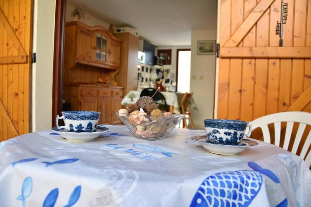 une table avec deux tasses bleues et blanches et un bol de fruits dans l'établissement Maison 3 pièces - Gruissan Ayguades AY060-B131, à Vires