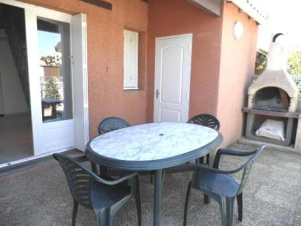 un patio avec une table, des chaises et une cheminée dans l'établissement Maison 2 pièces mezzanine - Gruissan Ayguades AY090-025, à Vires