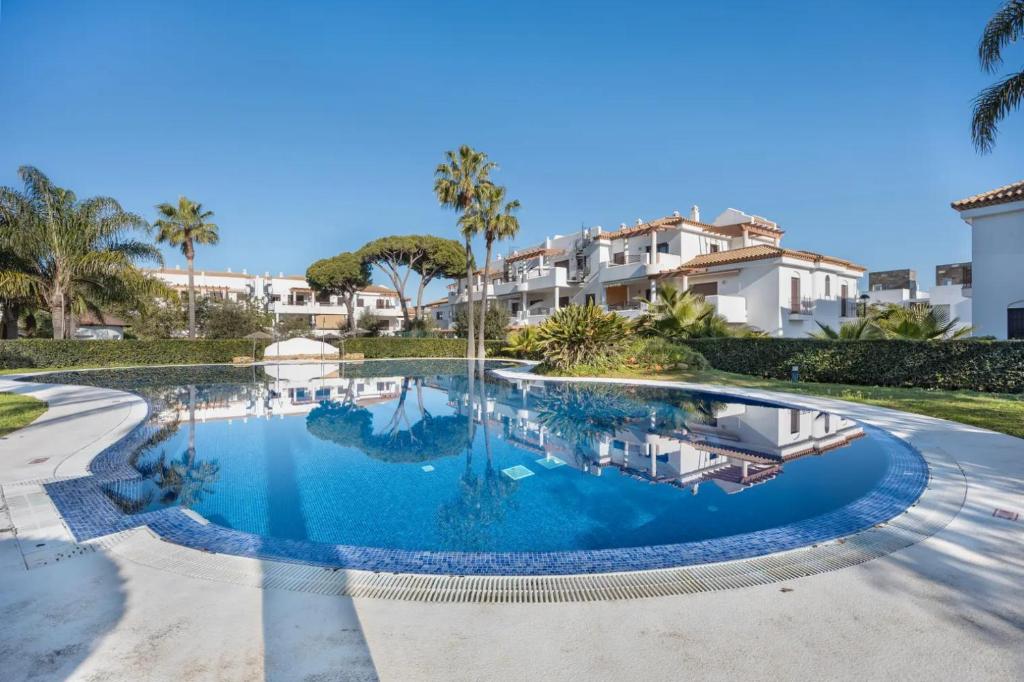 a swimming pool in a villa with palm trees at Golden Sands Apartment - Chiclana de la frontera in Novo Sancti Petri