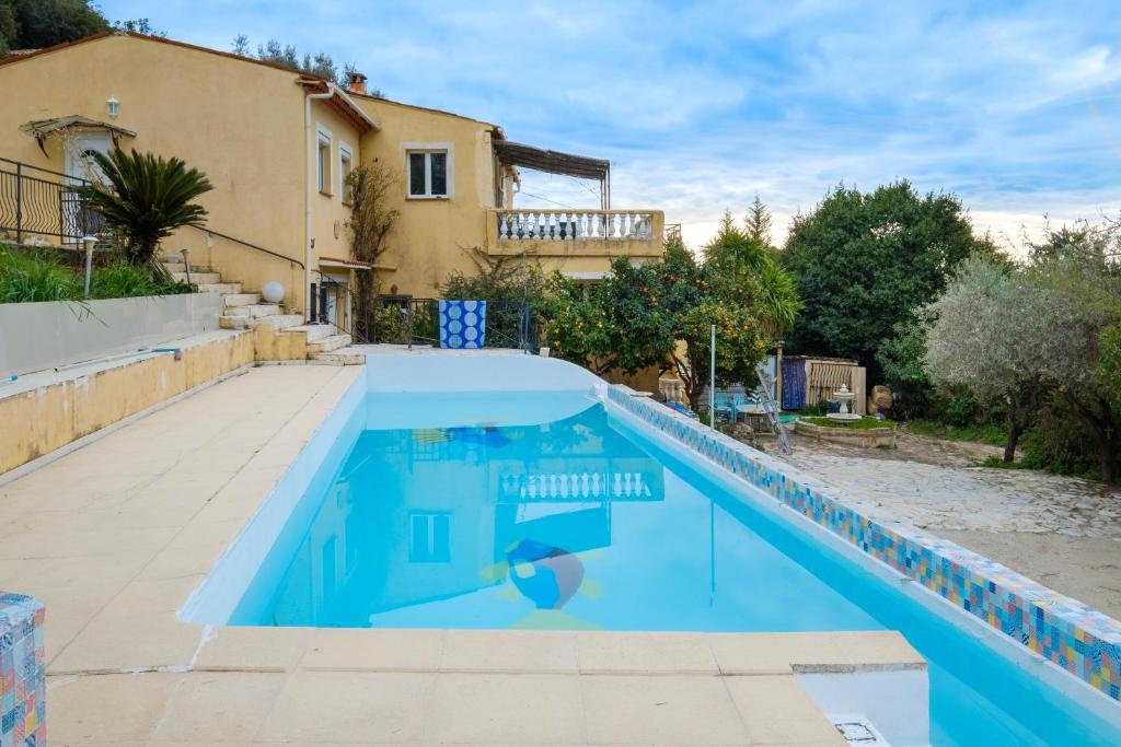 une piscine bleue avec une maison en arrière-plan dans l'établissement Appartement Falicon, à Falicon