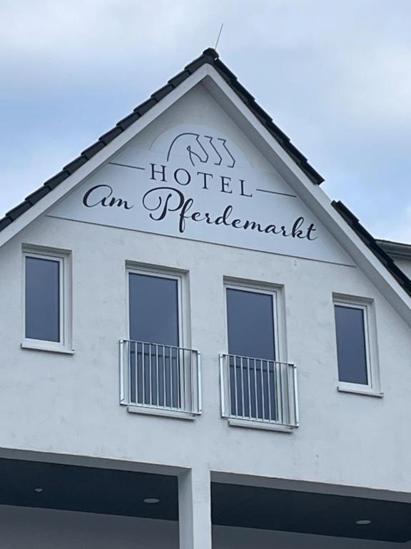 a white building with a sign on top of it at Hotel am Pferdemarkt in Aurich