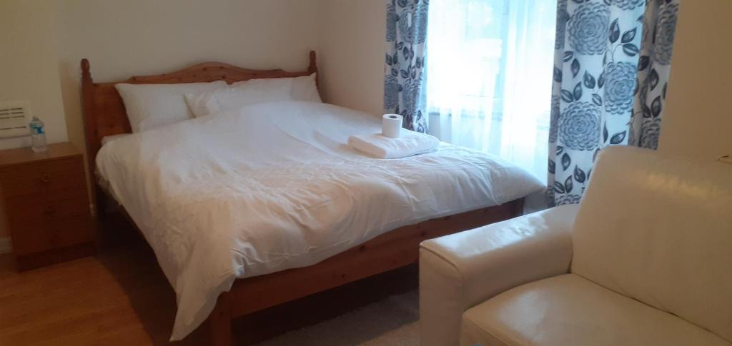 a bedroom with a bed and a chair and a window at TonyHomes in Dagenham