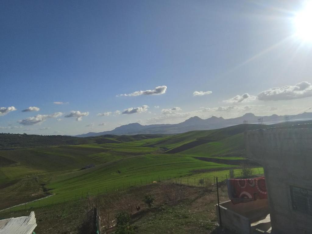 una vista de un campo verde con montañas en el fondo en L'ile de caroubier, en Taounate