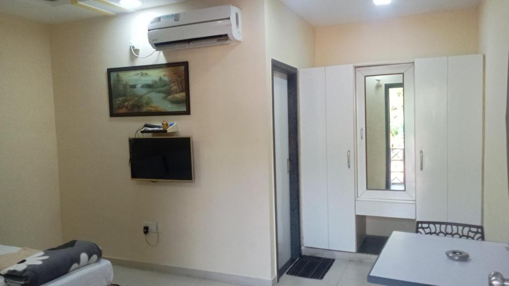 a living room with a television on the wall at Giriraj Garden Resort in Vāgholi