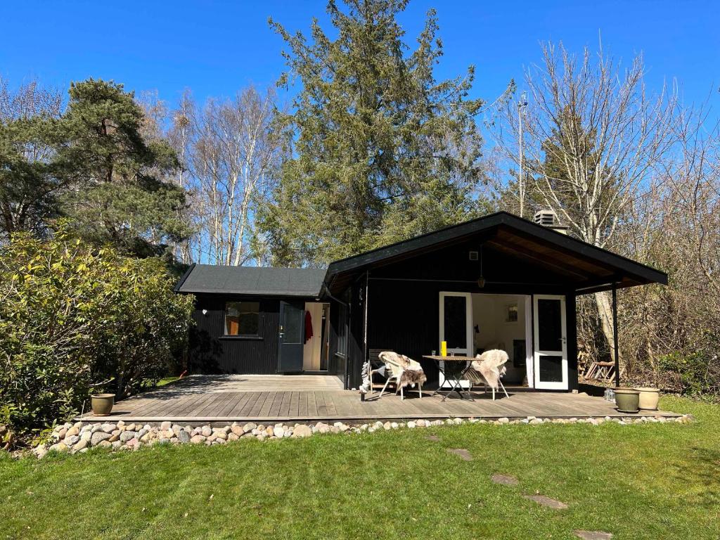 a black house with two animals sitting on a deck at Charming Cottage In Raageleje in Vejby