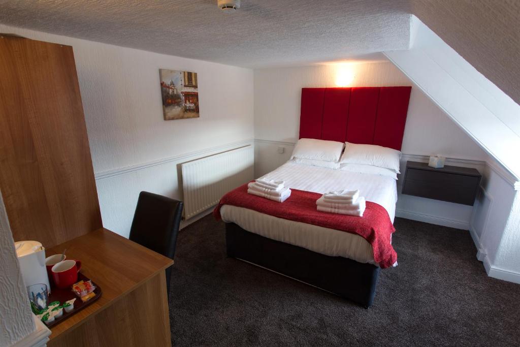 a small bedroom with a bed with a red headboard at Trinity Guest House in Hartlepool