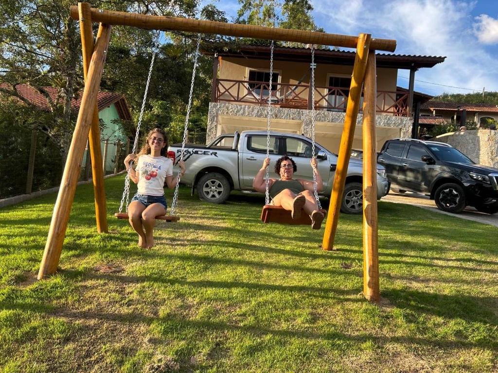 two women sitting on swings in a yard at A Casa do Júnior em Visconde de Mauá in Visconde De Maua