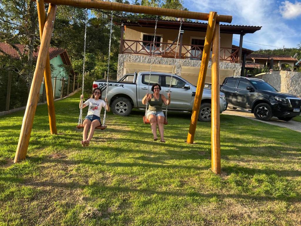 two women on a swing set in a yard at A Casa do Júnior em Visconde de Mauá in Visconde De Maua
