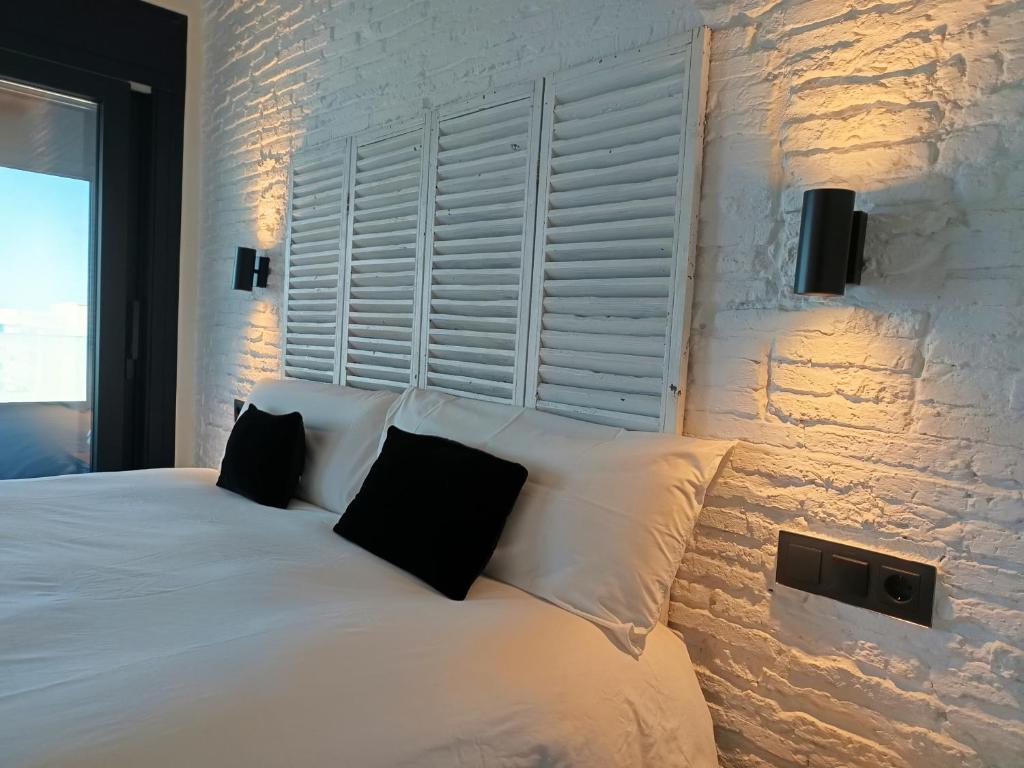 a bedroom with a white bed with two black pillows at El vigía de cadiz in Cádiz