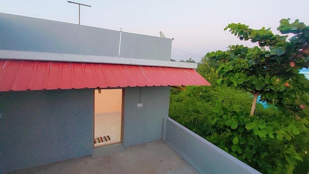 un edificio con techo rojo y árbol en Smiley HomeStay at Chidambaram, en Chidambaram