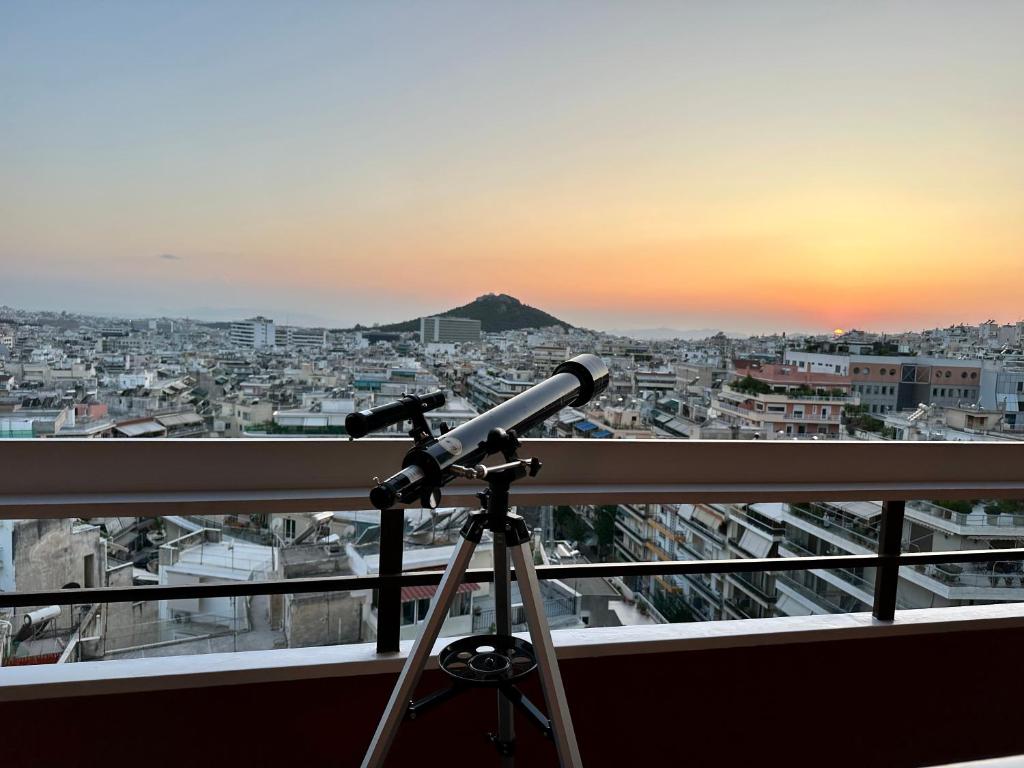 アテネにあるApollo Tower Athens Center 360oView Luxury Aptのバルコニーに設置された望遠鏡から街を眺める
