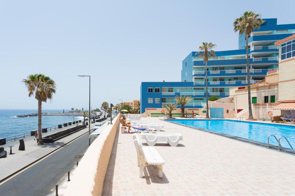 una piscina con panchine vicino all'oceano di Home2Book Cozy Coastal Duplex & Pool, Caletillas a Punta Larga