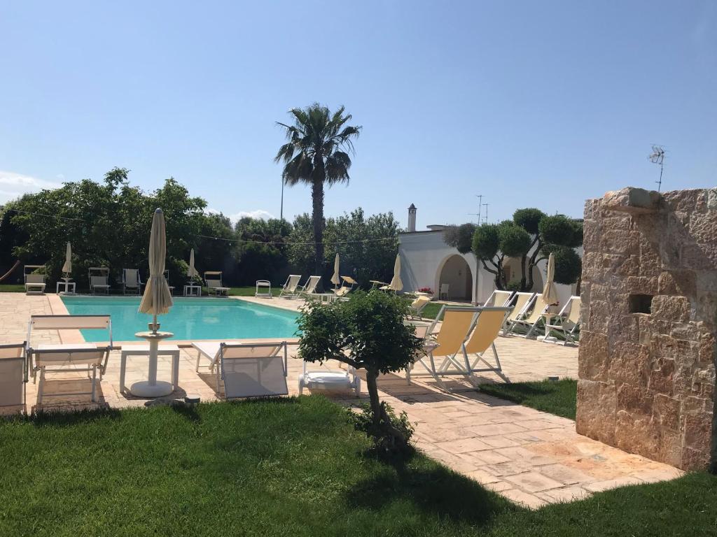 a pool with chairs and a table and a umbrella at Relais Masseria della Colomba - Agriturismo in Francavilla Fontana