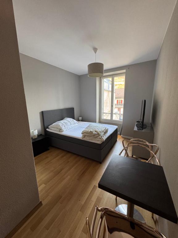 een slaapkamer met een bed, een tafel en een raam bij Chambre au centre ville in Martigny-Ville