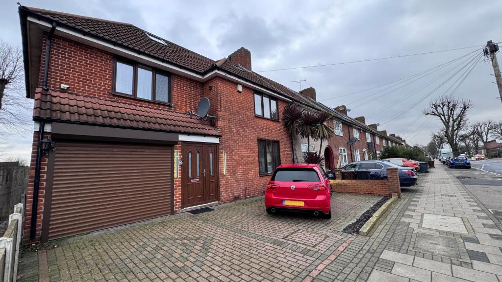 a small red car parked in front of a brick house at Large Modern Home Near Barking Station With SuperFast 1gbps Wi-Fi & Free Parking in Barking
