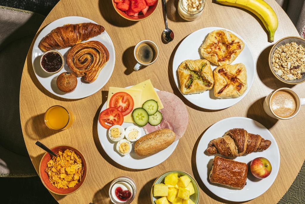 a wooden table with plates of breakfast food on it at Point A Hotel London Paddington in London