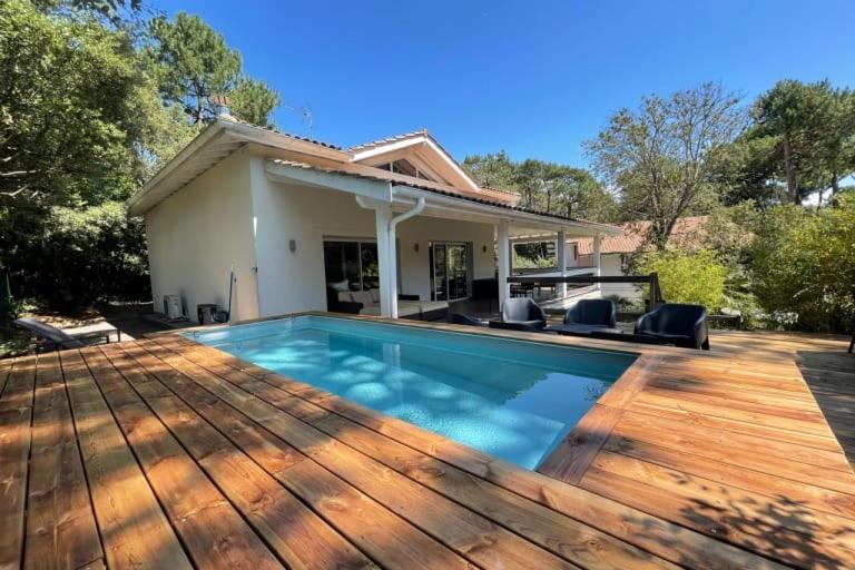 une maison avec une piscine et une terrasse en bois dans l'établissement Magnifique villa climatisée -10 personnes avec Piscine et pétanque - Pyla, à La Teste-de-Buch