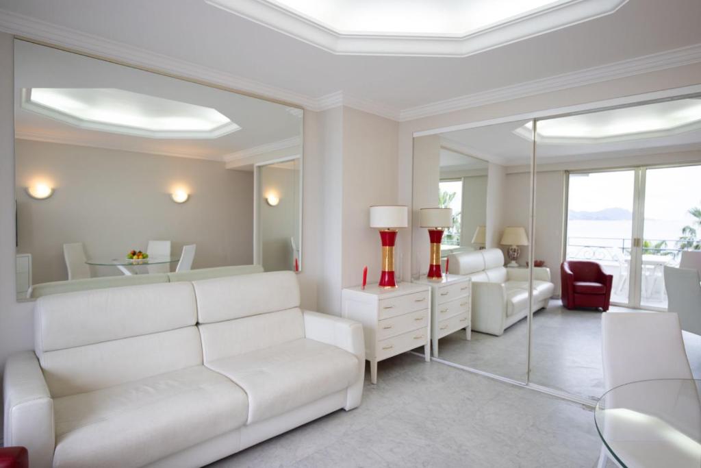Elle comprend un salon doté d'un mobilier blanc et d'un miroir. dans l'établissement One bedroom apartment with beautiful sea view, à Cannes