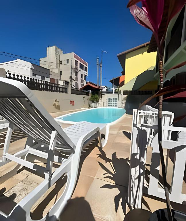 a white bench next to a swimming pool at Casa Entre o Mar e a Lagoa in Saquarema