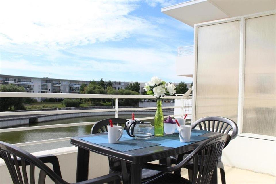 une table noire avec des chaises et un vase de fleurs sur le balcon dans l'établissement Appt 2 pièces LA ROCHELLE - LR030-E215, à La Rochelle