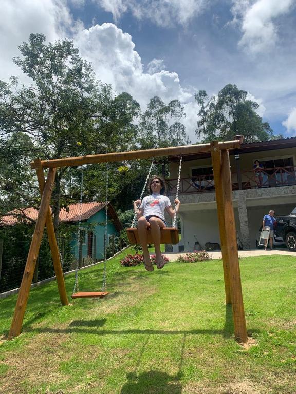a woman sitting on a swing in a yard at A Casa do Júnior em Visconde de Mauá in Visconde De Maua