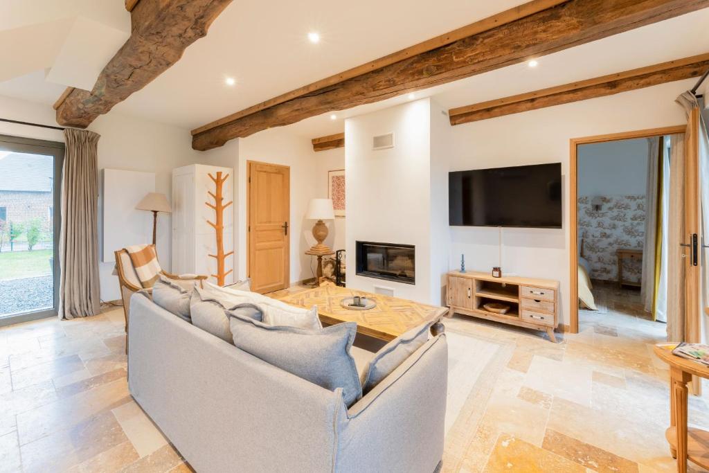 ein Wohnzimmer mit Sofa und Fernseher in der Unterkunft Maison Morny Your Exquisite Retreat near Deauville in Cricquebœuf